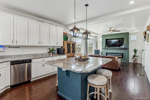 kitchen with a breakfast bar area, a center island, stainless steel dishwasher, pendant lighting, and white cabinets