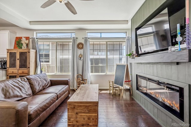 interior space featuring dark wood-style floors, a wealth of natural light, a glass covered fireplace, and a ceiling fan