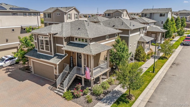 view of front facade with a garage, a shingled roof, a residential view, decorative driveway, and a porch