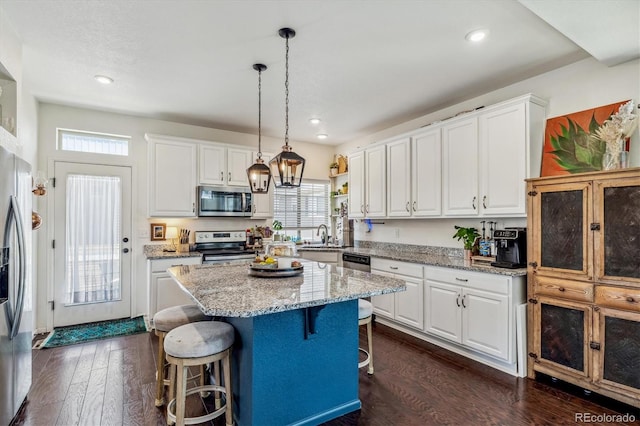 kitchen with dark wood-style floors, a breakfast bar, stainless steel appliances, white cabinetry, and a kitchen island