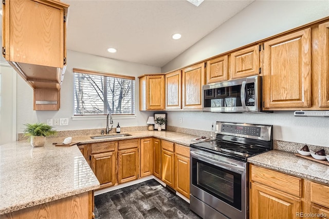 kitchen with light stone counters, sink, appliances with stainless steel finishes, and vaulted ceiling