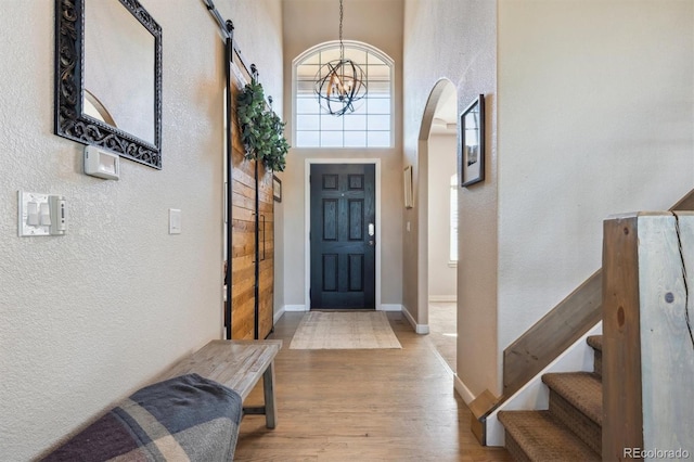 14953 Akron Ct, Brighton, CO 80602 - foyer featuring a textured wall, a chandelier, wood finished floors, arched walkways, and baseboards