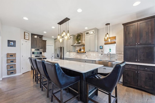 14953 Akron Ct, Brighton, CO 80602 - kitchen with wall chimney range hood, stainless steel refrigerator with ice dispenser, a sink, a kitchen island with sink, and a breakfast bar