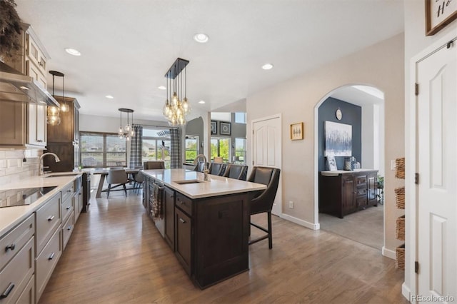 14953 Akron Ct, Brighton, CO 80602 - kitchen with arched walkways, black electric cooktop, a kitchen breakfast bar, a sink, and light countertops