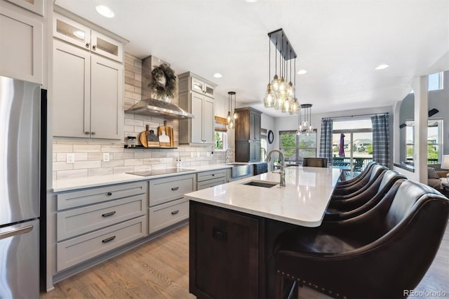 14953 Akron Ct, Brighton, CO 80602 - kitchen with wall chimney exhaust hood, freestanding refrigerator, a sink, black electric cooktop, and gray cabinets