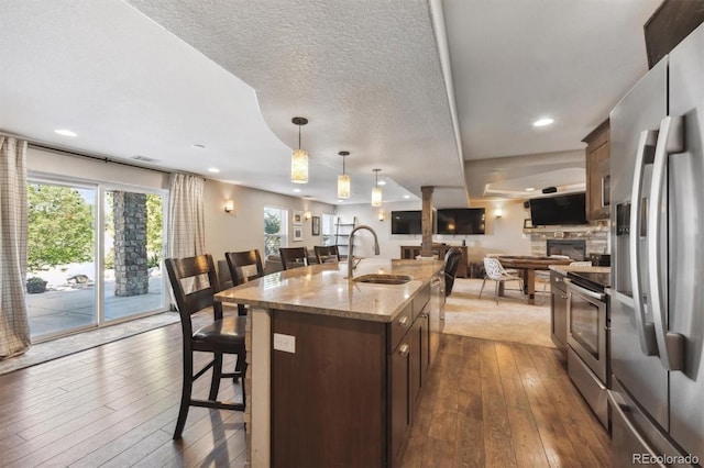 14953 Akron Ct, Brighton, CO 80602 - kitchen featuring stainless steel appliances, a sink, open floor plan, dark wood finished floors, and a kitchen bar