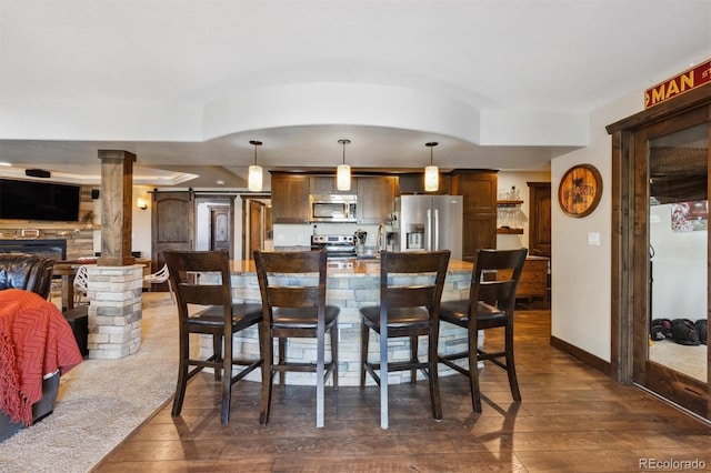 14953 Akron Ct, Brighton, CO 80602 - dining room with dark wood-style flooring, a stone fireplace, and baseboards