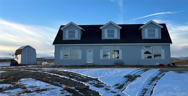 cape cod house featuring a storage unit