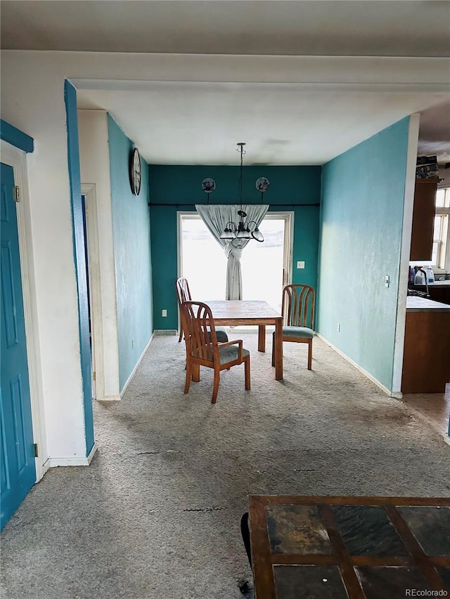 unfurnished dining area with carpet flooring, plenty of natural light, and an inviting chandelier