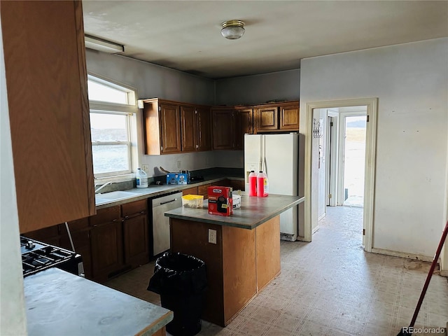 kitchen featuring white appliances, a center island, and sink