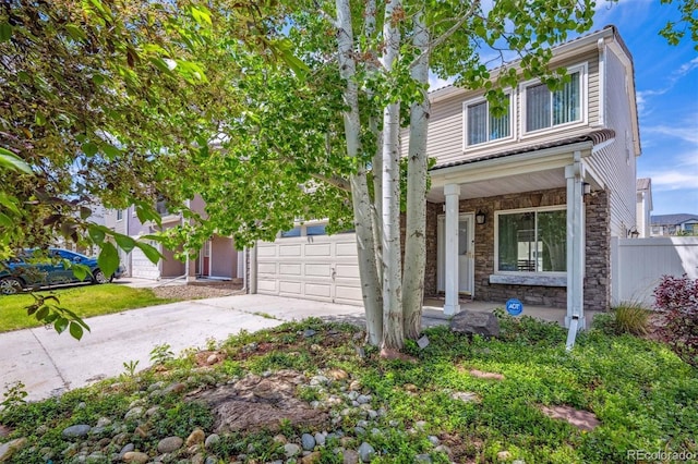 4435 Andes Ct, Denver, CO 80249 - view of front of home featuring stone siding, covered porch, concrete driveway, fence, and an attached garage