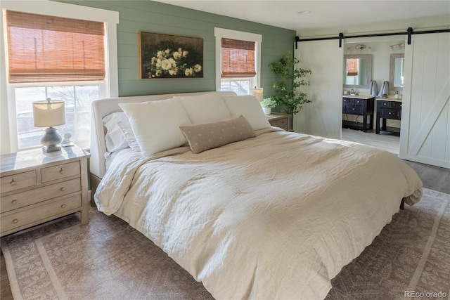 bedroom featuring dark wood-style floors, a barn door, and multiple windows