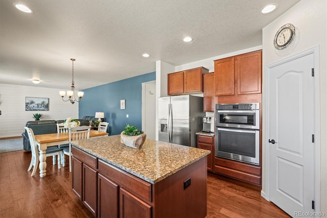 kitchen with decorative light fixtures, a kitchen island, stainless steel appliances, light stone counters, and a chandelier