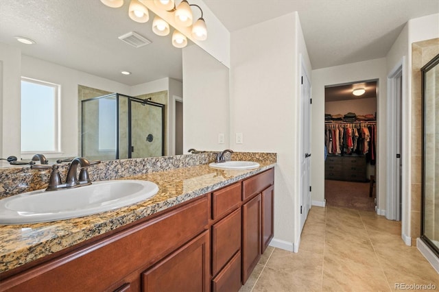 bathroom with a shower with shower door, vanity, and tile patterned flooring