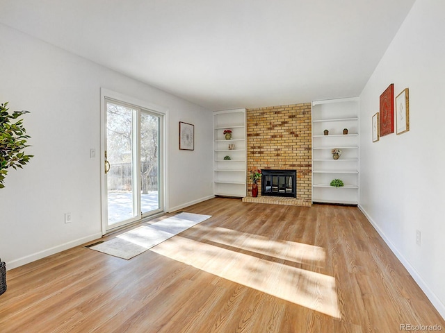 unfurnished living room with a brick fireplace and light wood-type flooring