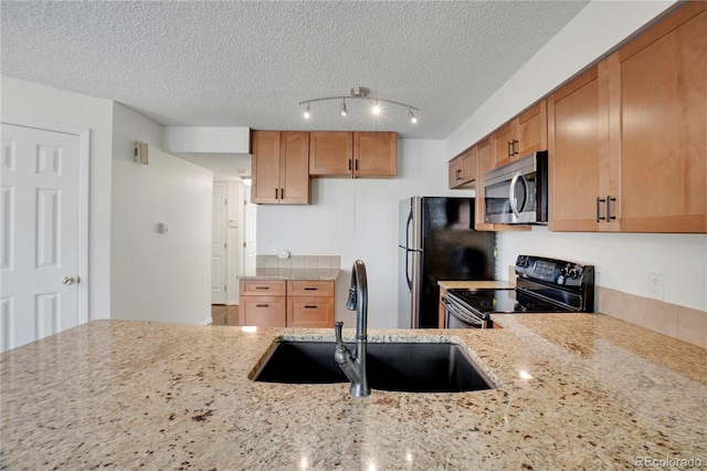 4802 E Kentucky Ave Unit E, Denver, CO 80246 - kitchen with appliances with stainless steel finishes, a sink, light stone counters, a textured ceiling, and brown cabinets