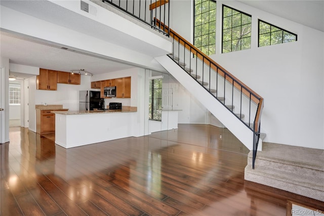 4802 E Kentucky Ave Unit E, Denver, CO 80246 - unfurnished living room with wood finished floors, stairs, healthy amount of natural light, and a high ceiling