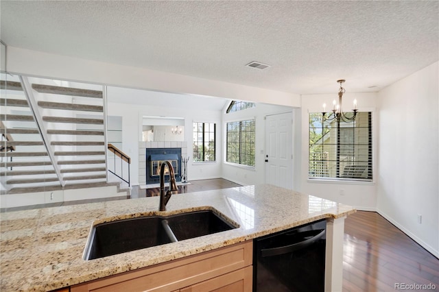 4802 E Kentucky Ave Unit E, Denver, CO 80246 - kitchen featuring black dishwasher, a sink, dark wood-type flooring, a chandelier, and a fireplace