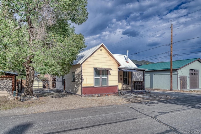 124 E 8th St, Salida, CO 81201 - view of front of home with fence, asphalt driveway, metal roof, an outbuilding, and a detached garage