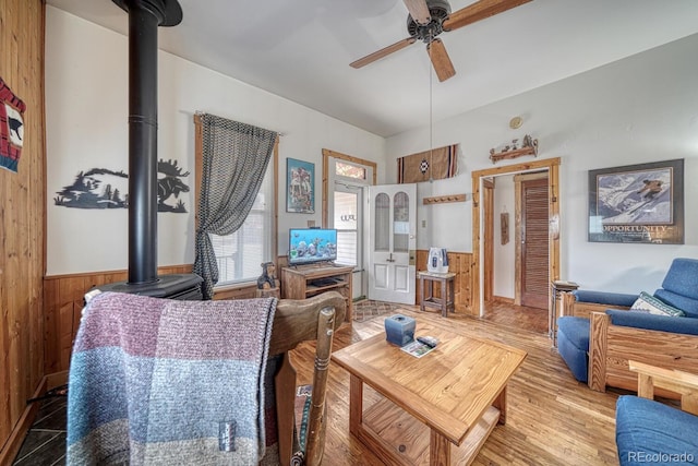 124 E 8th St, Salida, CO 81201 - living area with a wood stove, ceiling fan, wood finished floors, wooden walls, and a wainscoted wall