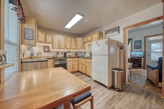 124 E 8th St, Salida, CO 81201 - kitchen with freestanding refrigerator, light brown cabinetry, black oven, light wood-style floors, and dark countertops