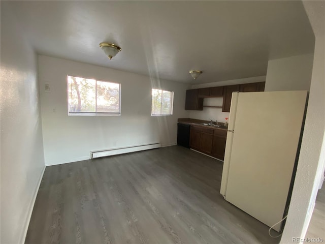 kitchen with a sink, wood finished floors, freestanding refrigerator, a baseboard radiator, and baseboards