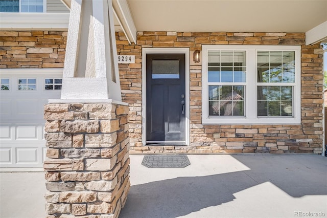 19294 E Warren Pl, Aurora, CO 80013 - doorway to property with stone siding, covered porch, and a garage