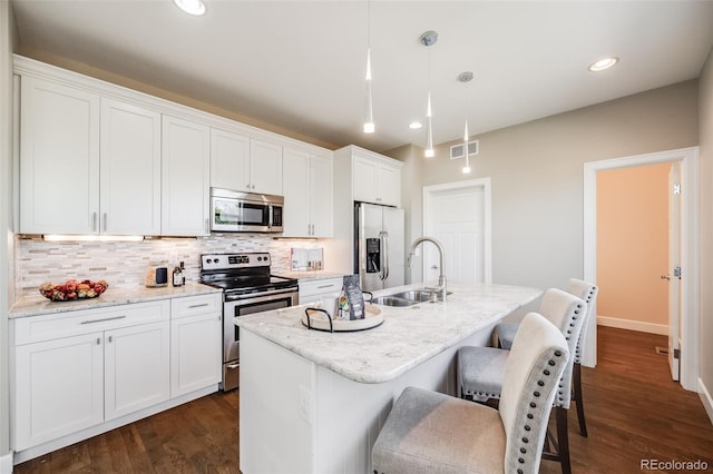 19294 E Warren Pl, Aurora, CO 80013 - kitchen featuring stainless steel appliances, tasteful backsplash, a kitchen island with sink, white cabinets, and a breakfast bar area