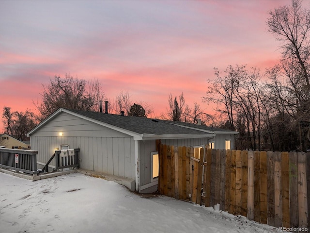 exterior space featuring a shingled roof, fence, and a deck