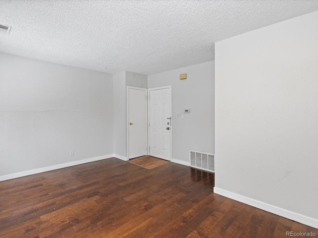 spare room featuring baseboards, a textured ceiling, visible vents, and wood finished floors