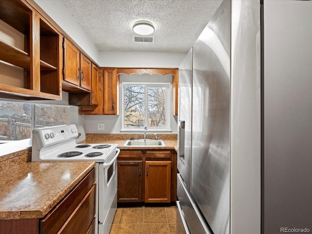 kitchen with white electric range, a sink, visible vents, stainless steel fridge with ice dispenser, and brown cabinets