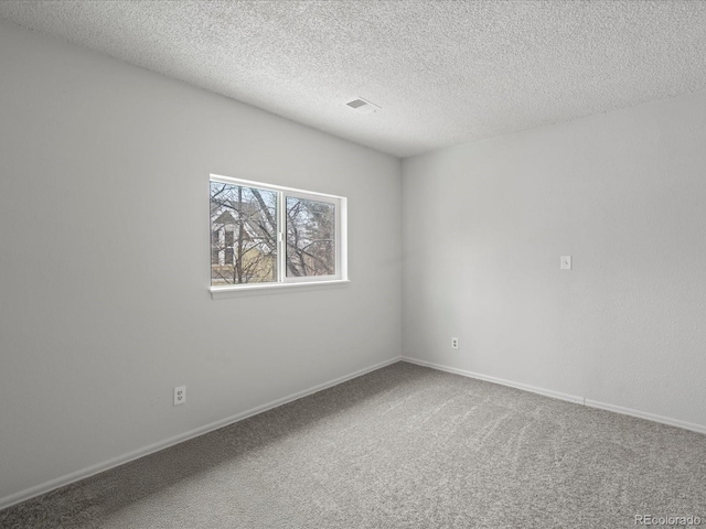 carpeted empty room with visible vents, a textured ceiling, and baseboards