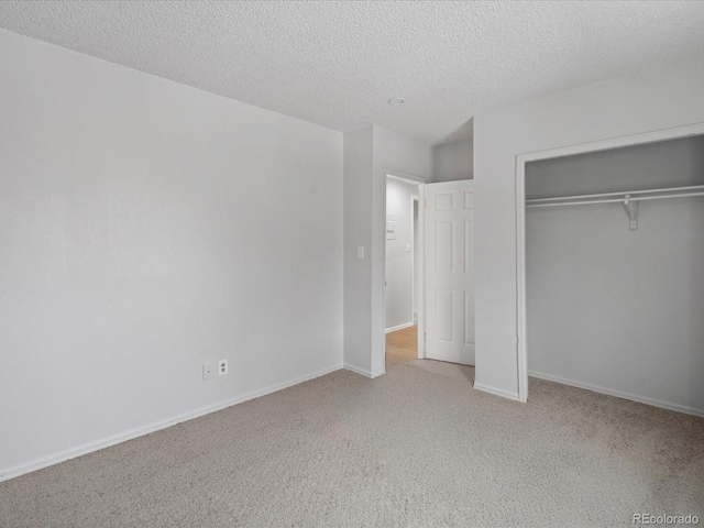 unfurnished bedroom featuring carpet floors, a textured ceiling, baseboards, and a closet