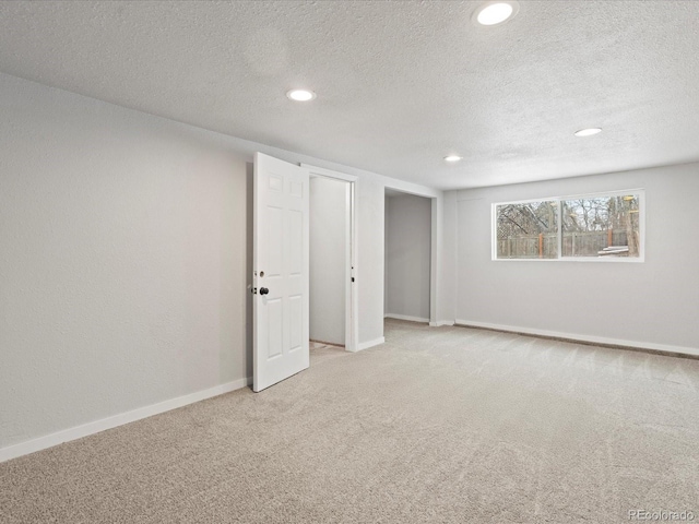 basement featuring a textured ceiling, baseboards, carpet flooring, and recessed lighting