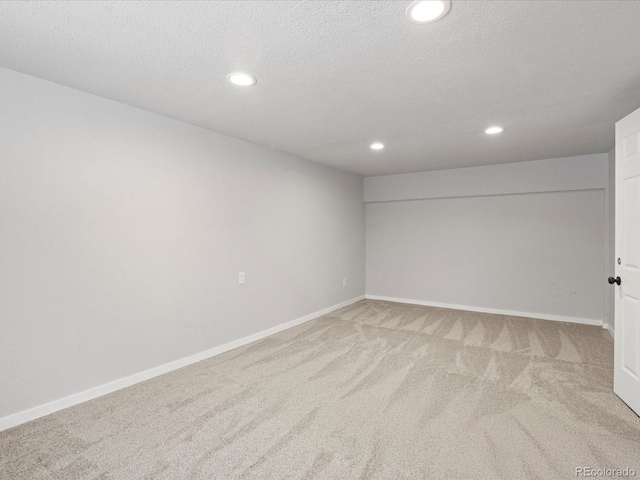 spare room featuring recessed lighting, light colored carpet, a textured ceiling, and baseboards