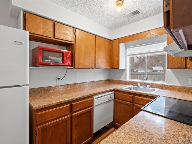 kitchen featuring white appliances, visible vents, light countertops, a textured ceiling, and a sink