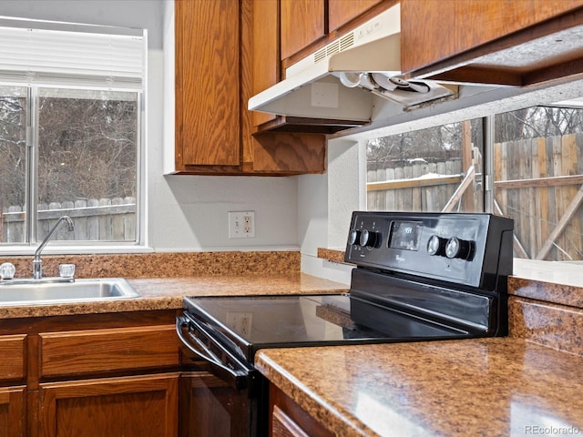 kitchen with under cabinet range hood, a sink, black electric range, light countertops, and brown cabinets