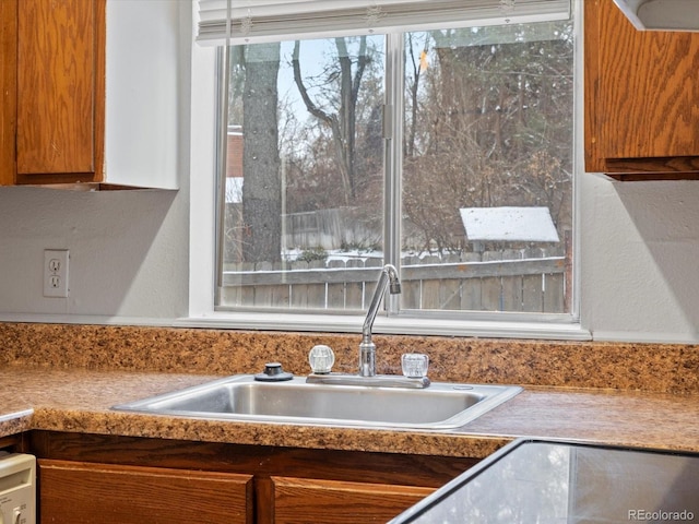 kitchen featuring light countertops, a sink, and brown cabinets