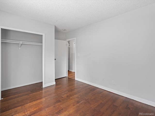 unfurnished bedroom featuring a textured ceiling, a closet, baseboards, and wood finished floors