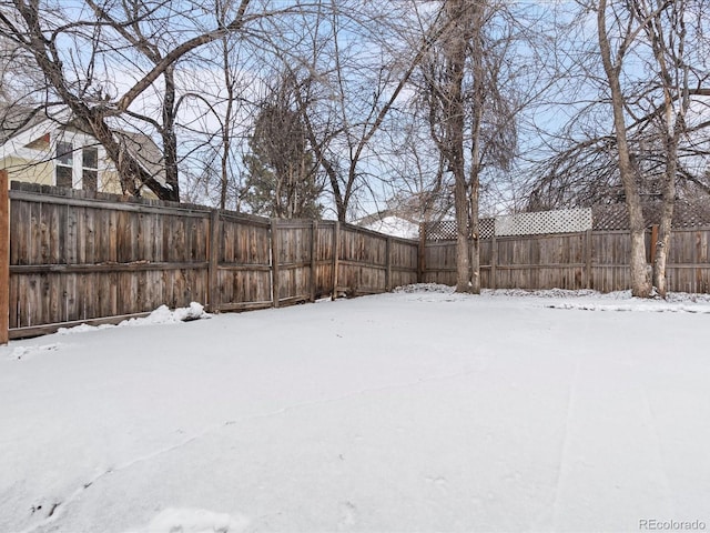 snowy yard featuring a fenced backyard