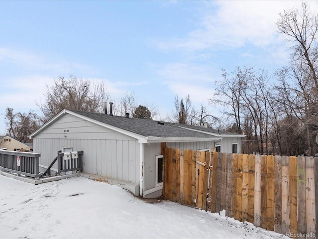 exterior space with a deck, roof with shingles, and fence