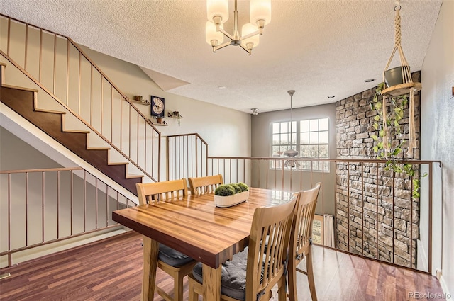 dining area with a textured ceiling, a wainscoted wall, wood finished floors, and a chandelier