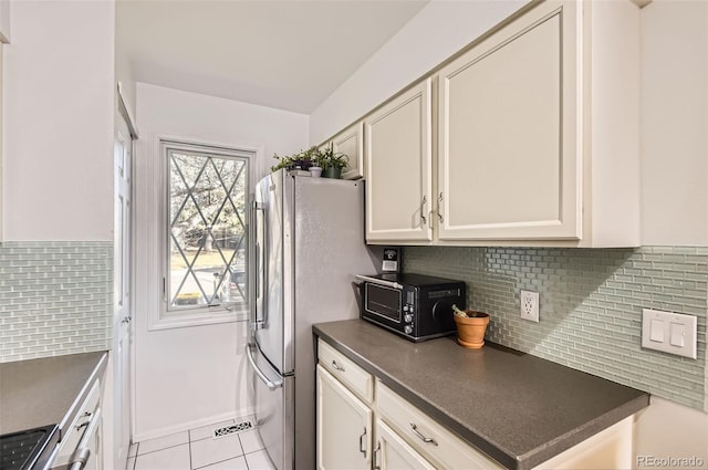 kitchen featuring light tile patterned floors, tasteful backsplash, dark countertops, and white cabinets