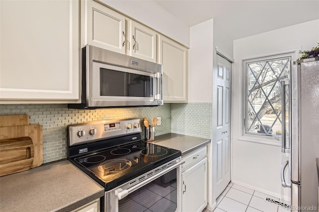 kitchen featuring white cabinetry, appliances with stainless steel finishes, decorative backsplash, and light tile patterned flooring