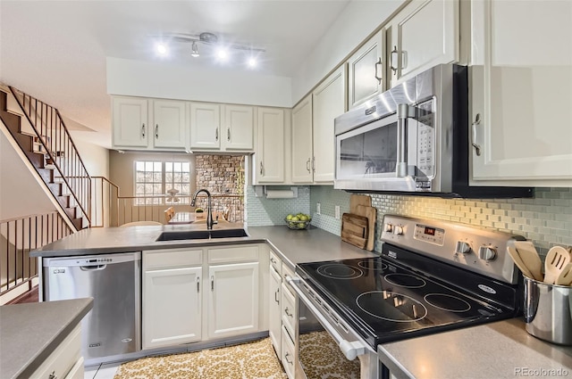 kitchen with a peninsula, decorative backsplash, stainless steel appliances, and a sink