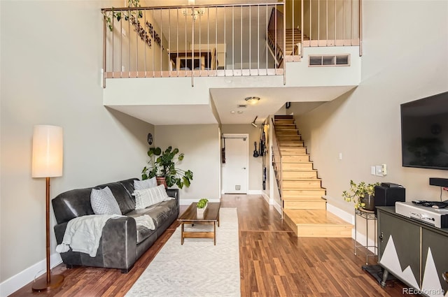 living room featuring stairway, wood finished floors, visible vents, and baseboards