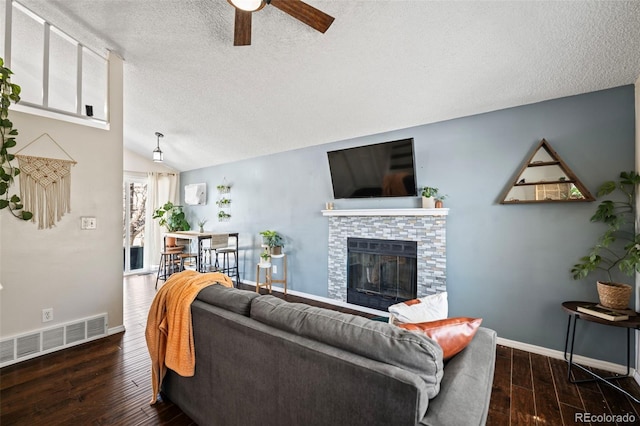 living room featuring a textured ceiling, a stone fireplace, ceiling fan, and lofted ceiling