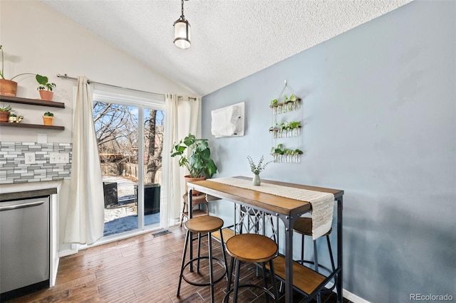 dining area with a textured ceiling, dark wood-type flooring, and lofted ceiling