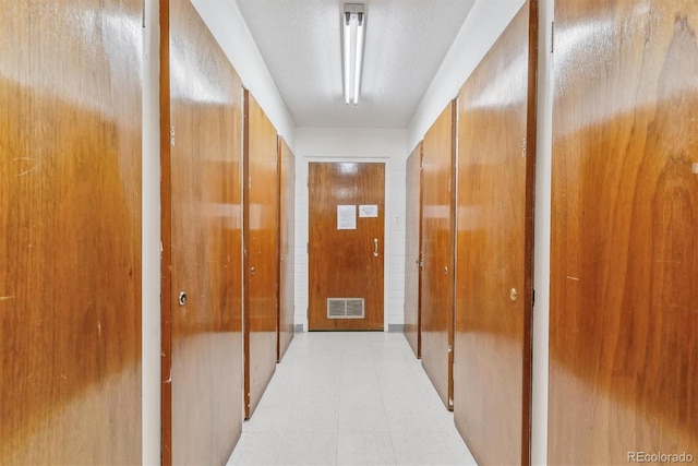 hall with visible vents, light floors, and a textured ceiling