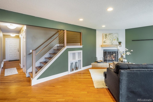 living room with recessed lighting, light wood-style flooring, a textured ceiling, and stairway